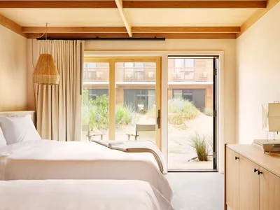 A minimalist bedroom featuring wood elements and a view of the beach outside.