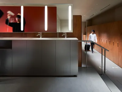 A modern, minimalist locker room interior with concrete furnishings and a sleek counter.
