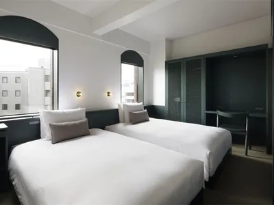 A minimalist bedroom with white textured surfaces and a white bed.