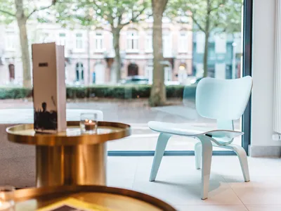 A modern restaurant interior featuring a polished cement floor with a sleek white chair and a menu on a brass table.