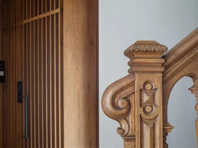 A detailed wooden staircase with ornate carvings and a wooden wall.