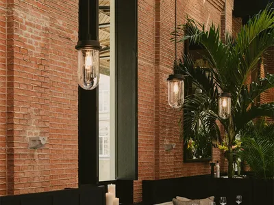 A restaurant interior with brick walls and pendant lights.
