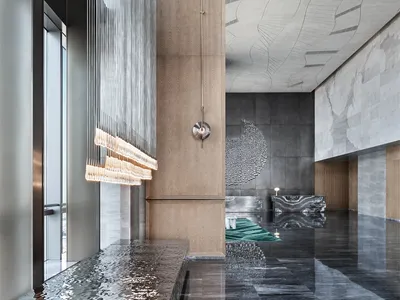 Modern hotel lobby with marble, concrete, and wooden elements.