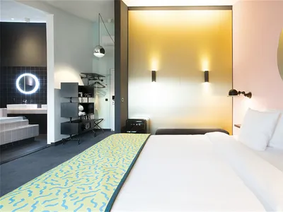 Modern hotel room with a bed, bathroom, and minimalistic design.