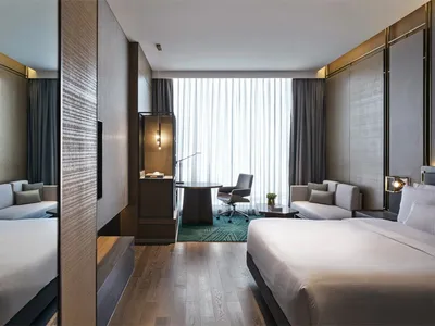 Modern hotel suite with a wooden floor, fabric furnishings, and glass windows.