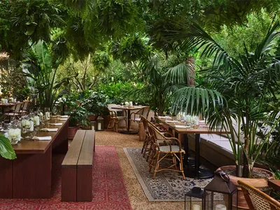 優雅布置的餐廳露台，搭配藤編家具、木質餐桌、綠植與布料點綴，適合室內外用餐。