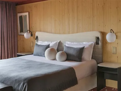 Modern bedroom with a gray bed and wooden walls.