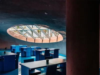 A modern restaurant interior with blue furniture and a large oval window.