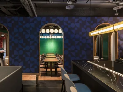 A modern restaurant interior with geometric patterns on the walls and a long dining table.