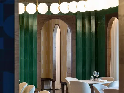 Modern restaurant interior featuring wood, curved glass, and green tiles.