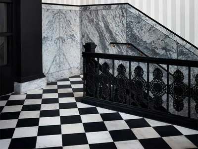 A black and white marble staircase interior with striped wallpaper.