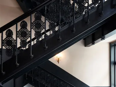 A grand black iron staircase with ornate railings and lighting in an interior setting.