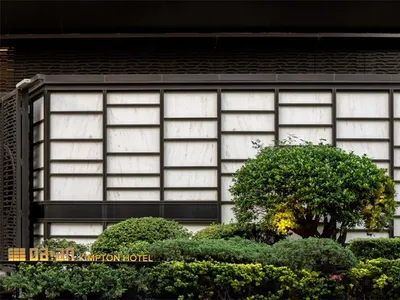 Kimpton Hotel exterior showcasing marble facade with green plants and glass elements.