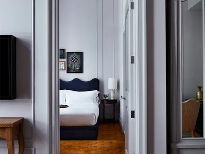 Modern bedroom with grey and white color palette, featuring a black upholstered bed, wooden floor, and framed art on the wall