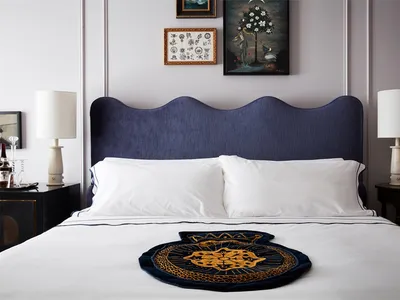 A modern minimalistic bedroom featuring a blue upholstered bed with white bedding and a decorative pillow on a white mattress