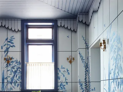 A modern restaurant interior with blue tiles, floral wall murals, and white tables.