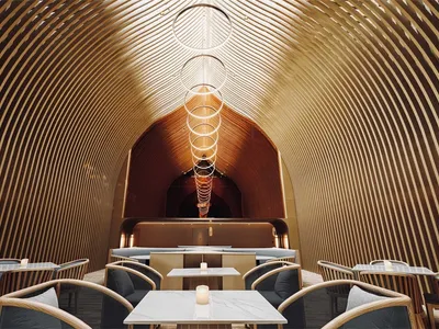 A modern restaurant interior featuring wooden elements and circular light fixtures.