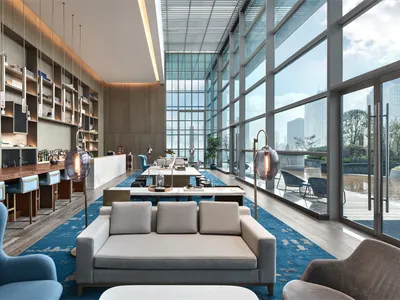 A modern hotel lobby featuring glass walls and concrete furniture.