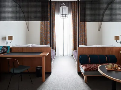 A modern bedroom interior featuring wooden furniture, cotton bedding, and iron accents.