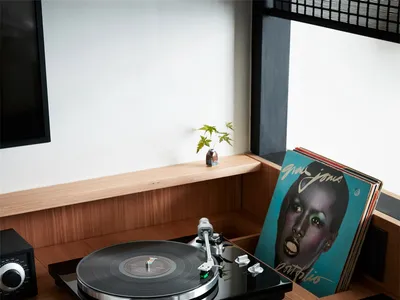 A modern home office setup featuring a wooden desk with a record player and records.