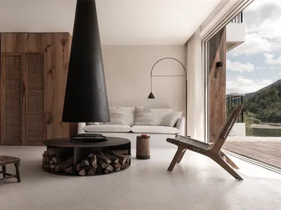 A minimalist living room with concrete walls and floors, featuring a modern fireplace and lounge furniture.