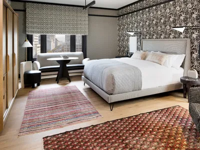 A modern bedroom featuring a upholstered bed adorned with striped bedding, a geometrically designed wooden coffee table, and