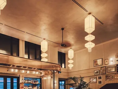 An industrial-style restaurant with marble tables, metal elements, and wooden chairs.