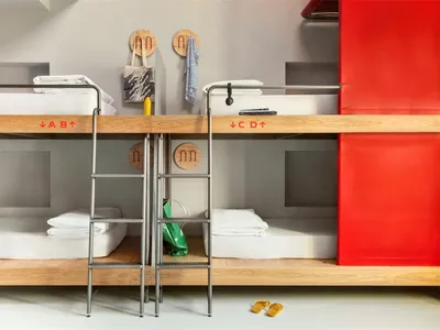 A modern bedroom featuring wooden bunk beds with red accents.