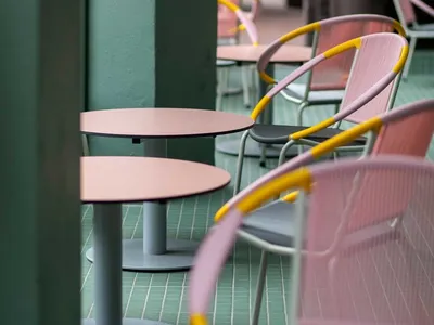 Pink and yellow metallic frame chairs and tables in a modern restaurant setting.