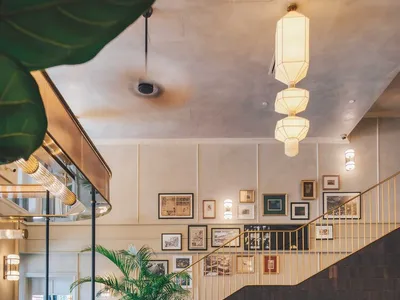 The interior design of a brass bar restaurant showcases a stylish, modern space with brick tile flooring, green foliage, and