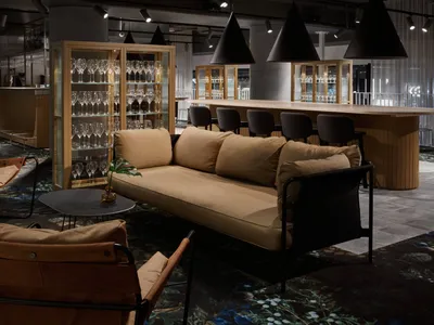 Contemporary hotel lounge featuring wooden furniture, glass cabinets, and leather accents.