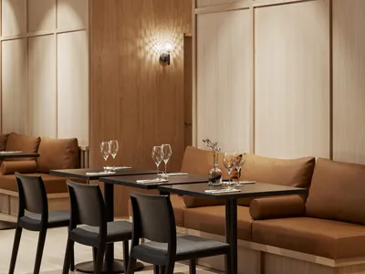 Modern restaurant interior with brown wooden walls and cushions, wooden tables with wine glasses, and black and gray cushions