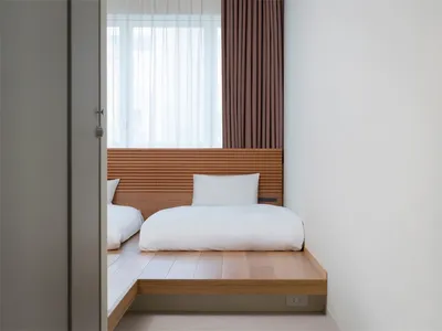 A minimalist bedroom featuring wooden flooring and a simple, uncluttered design.