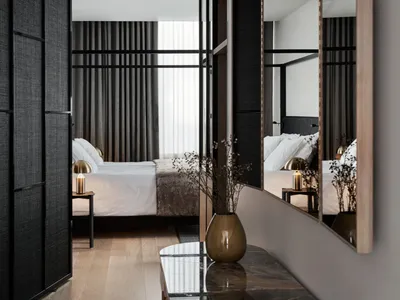 A minimalist bedroom featuring fabric bedding, a wooden floor, and metallic accents.