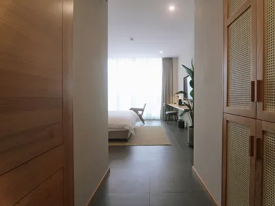 A minimalist bedroom with wooden furniture and a white bed.
