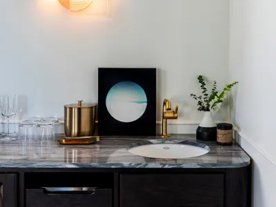 A modern bar with a marble countertop featuring a sink, faucet, and decorative items.