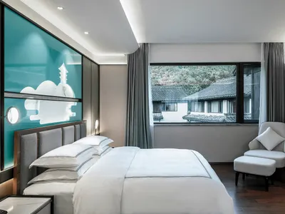 A minimalist bedroom featuring a white fabric bed and modern furniture.
