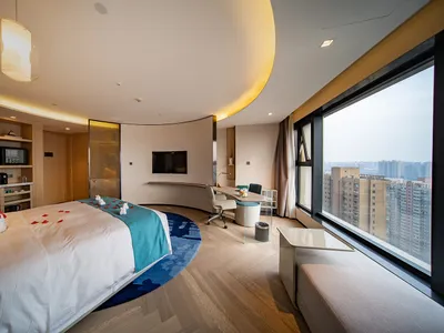 Modern hotel room with wooden floor, glass window, and fabric bedding.