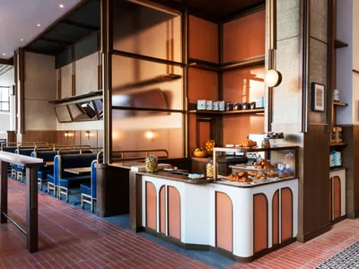 Modern restaurant cafe interior with seating, counter, and display case.