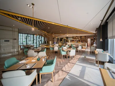 An interior photograph of a modern restaurant featuring wooden tables, glass and metal structures, and a contemporary design.