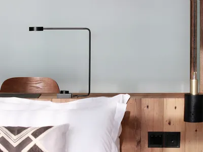 A minimalist bedroom featuring wooden walls and a white pillow.