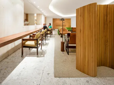 Mid-century modern restaurant lounge with white marble floor, wooden seating, and leather chairs