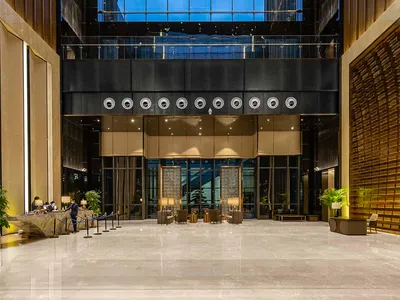 Modern hotel lobby featuring a glass atrium and marble flooring.