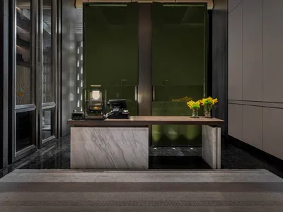 A modern hotel lobby with a marble desk and glass walls.