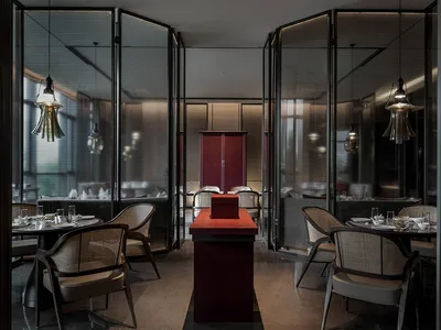 A sleek, minimalist restaurant interior featuring metallic tables and chairs.