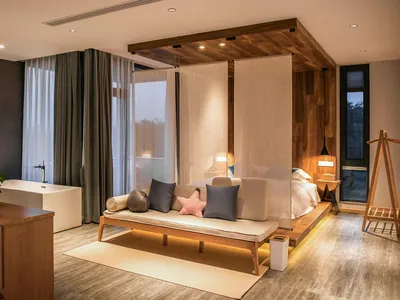 A minimalist bedroom featuring a wooden bed with linen bedding, a modern bathtub, and a minimalist design aesthetic.
