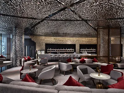 A modern hotel lounge area with metallic texture ceiling and fabric seating.