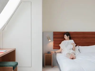 一位女士坐在臥室裡的現代簡約白色床上。