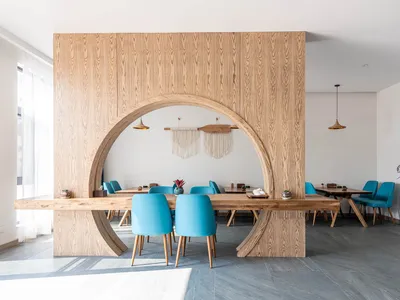 A modern minimalist restaurant interior with wooden furniture and blue chairs.