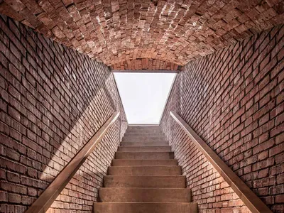 Indoor staircase with brick walls and a skylight at the top.